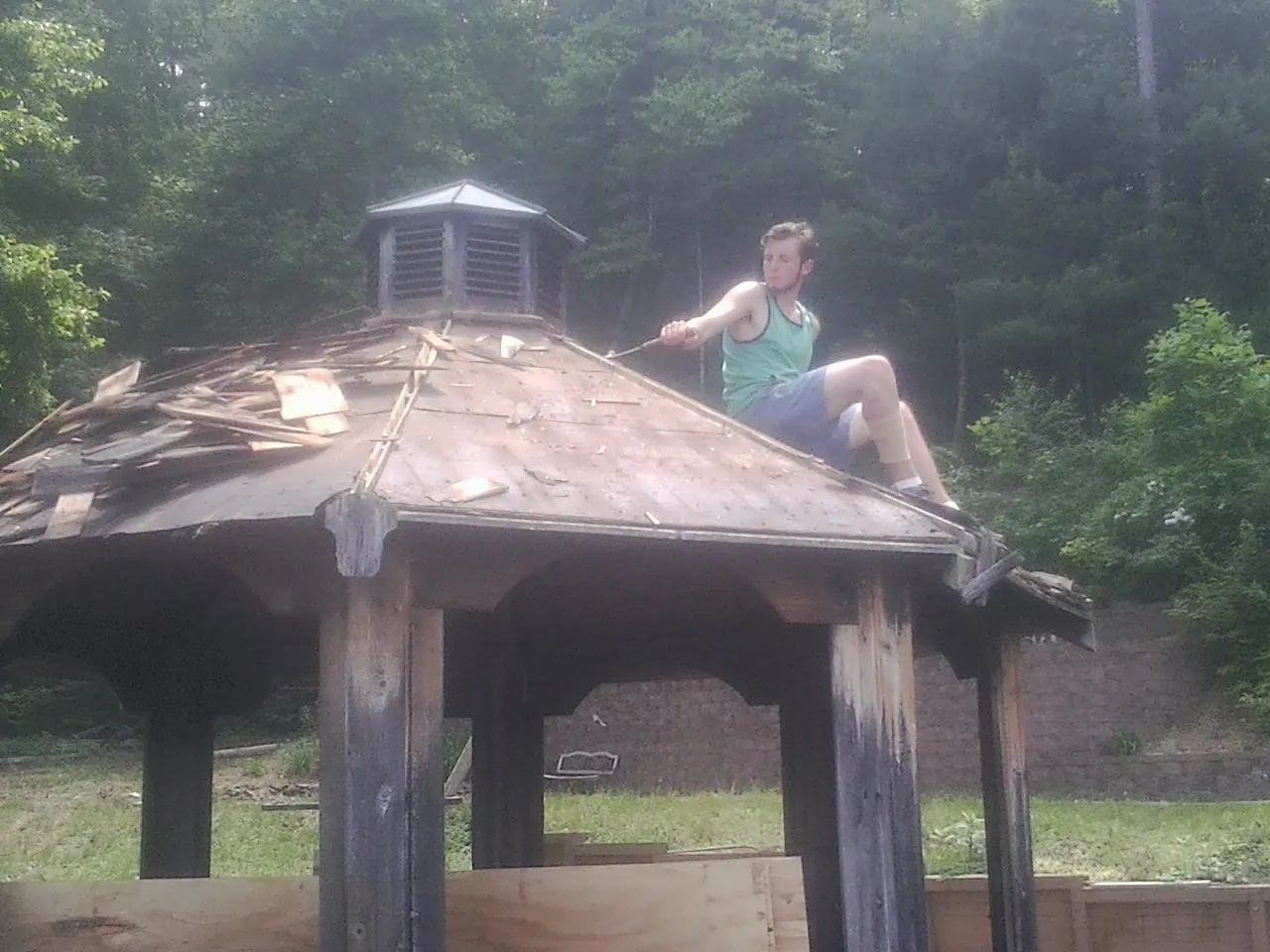 Tearing the old roof off a wooden gazebo before new shakes in Elmira