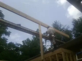 Carpenter setting a ridge beam over a new addition frame — Ice Dam Removal by Roofing Brothers in Elmira