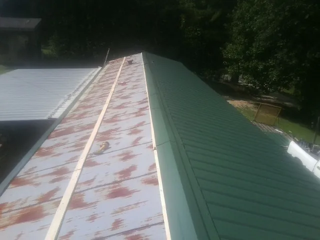 Old rusted panels beside newly installed green metal roofing — Wind Damage Roof Repair by Roofing Brothers in Elmira